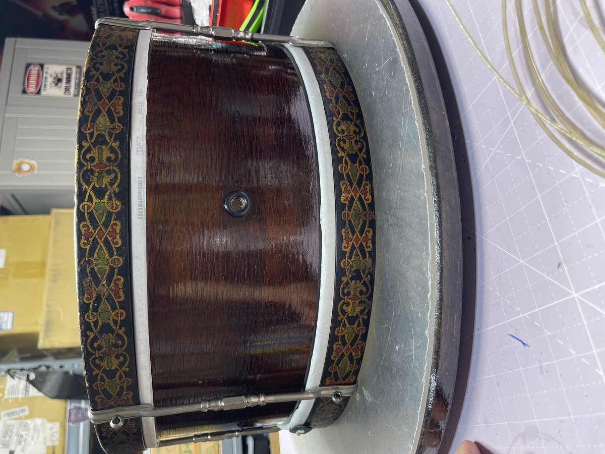 Antique Harmony snare drum with ornate gold and red inlaid band decoration on a dark wood shell
