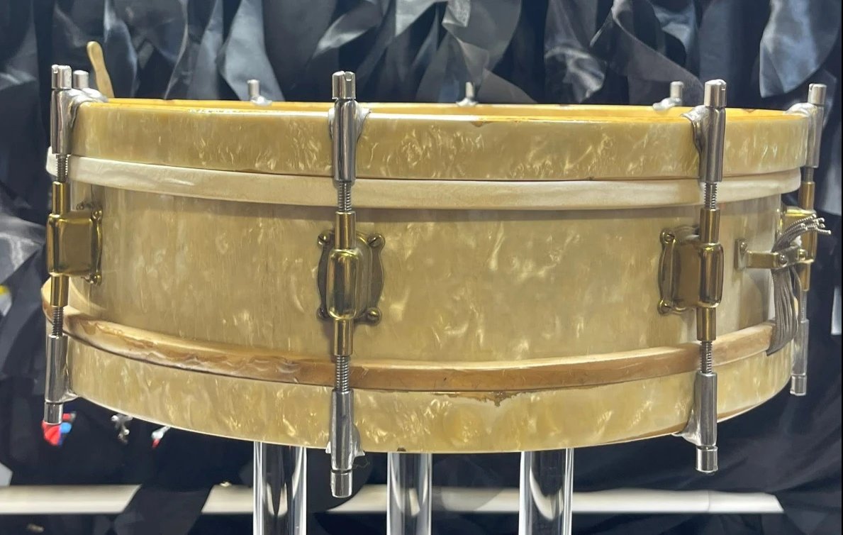 Side view of the Jedson De Luxe snare drum showing the white marine pearl wrap, pearl-wrapped hoops, and brass tube lugs with nickel tension rods